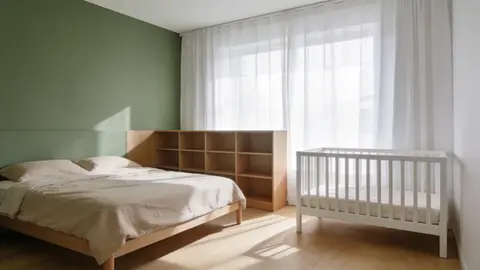 Спальня родителей и детская в одной комнате: двуспальная кровать, белая кроватка и низкий стеллаж-разделитель в скандинавском стиле